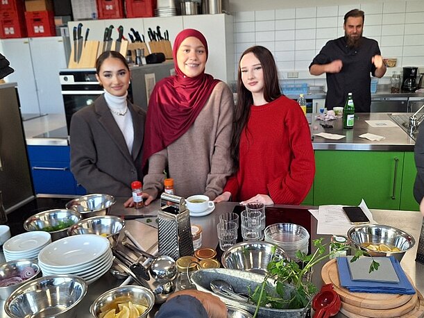 Schülerinnen in der Schulküche vor Schüsseln mit zubereiteten Speisen