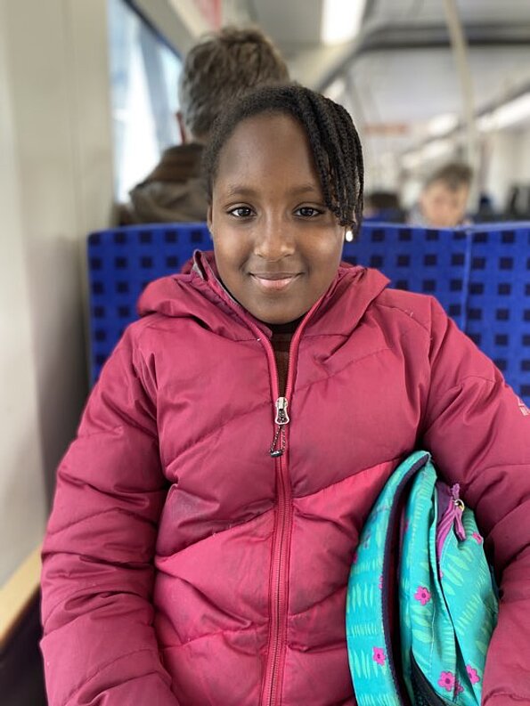 Rouguiatou Jalloh lächelt mit Rucksack in der Bahn