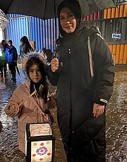 Mädchen mit Laterne und Mutter mit Regenschirm beim Laternenumzug im Regen