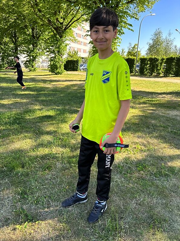 Beran in neongelbem Shirt auf einer Wiese im Park