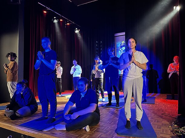 Yoga-Vorführung mit Gebetshaltung auf Matten im Scheinwerferlicht