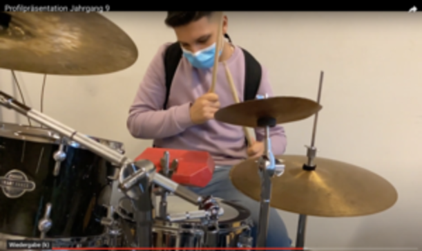 Schüler mit Maske spielt Schlagzeug im Profil Musik- und Videoproduktion