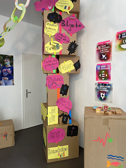 Turm aus Kartons mit bunten Zetteln und Papierketten bei der Vernissage KIDS417