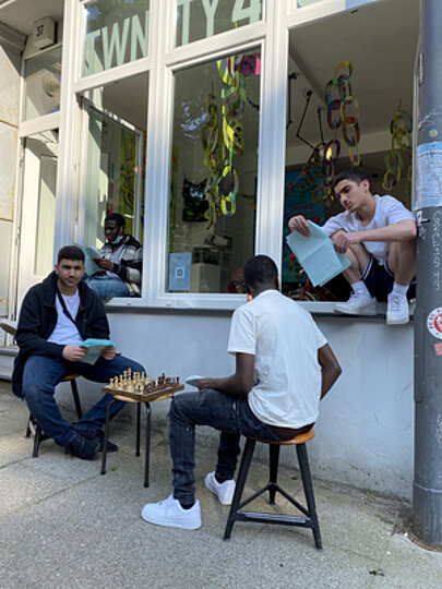 Jugendliche spielen Schach vor dem Fenster der Galerie twnty4svn