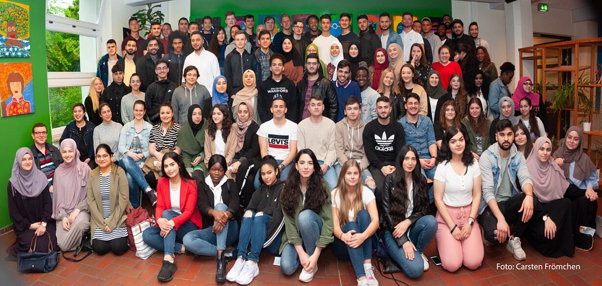 Großes Gruppenfoto des Abiturjahrgangs 2019 vor einer bunten Wand