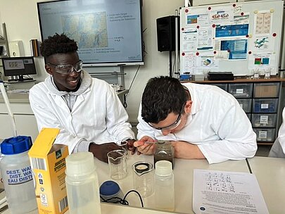 Zwei Schüler mit Schutzbrillen untersuchen Proben am Labortisch