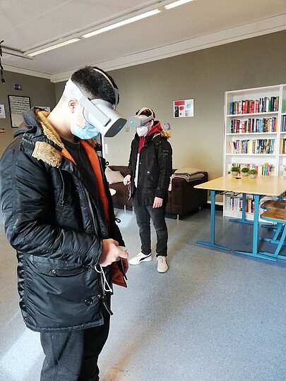 Zwei Jugendliche testen VR-Brillen im Raum mit Bücherregal