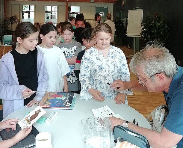 Axel Scheffler signiert Bücher für Kinder an einem runden Tisch