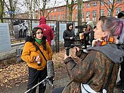 Schülerin mit Mikrofon wird am Ausstellungszaun „Zinn durch die Zeit“ gefilmt