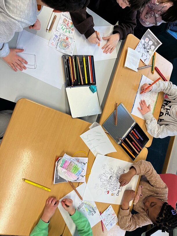 Kinder zeichnen und malen an Tischen beim Forschertag
