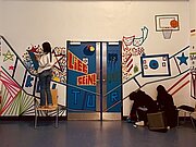 Schülerinnen gestalten Flurwand und Türen mit buntem Klebeband