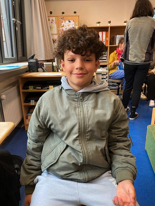 Moe aus der 4d sitzt lächelnd im Klassenraum beim Diversitätstag