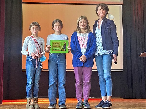 Siegerteam mit Lehrerin bei der Ehrung für den ersten Preis auf der Bühne