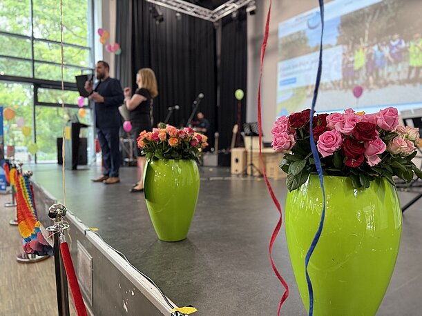 Bühne mit Rosenvasen und Moderation bei der Entlassungsfeier Jahrgang 10