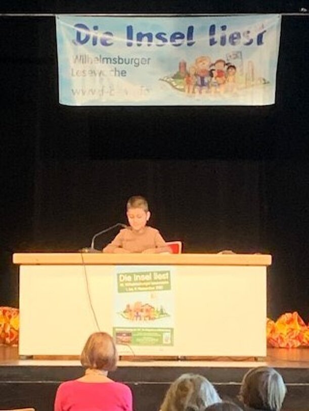 Lesung auf der Bühne unter dem Banner Die Insel liest