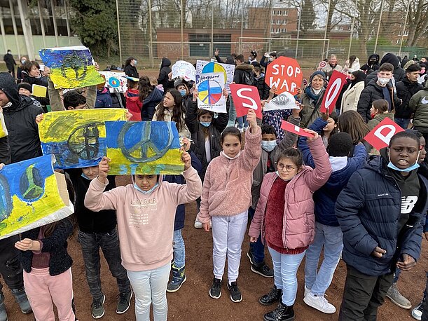 Kinder halten blau-gelbe Peace-Plakate und „Stop War“-Schilder