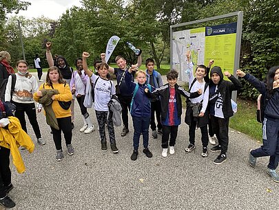Jubelnde Schülerinnen und Schüler vor der Infotafel der Park Sport Insel