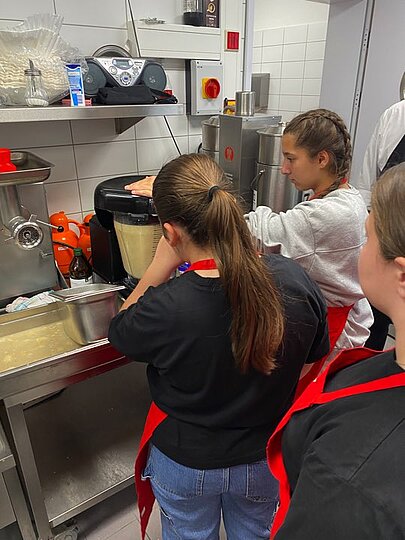 Schülerinnen probieren Küchengeräte in der Großküche aus