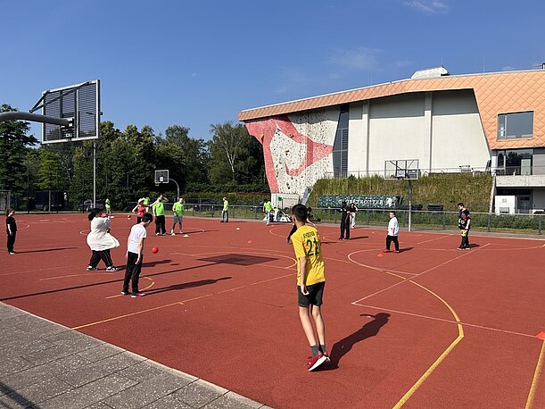 Jugendliche spielen auf einem roten Sportplatz im Inselpark