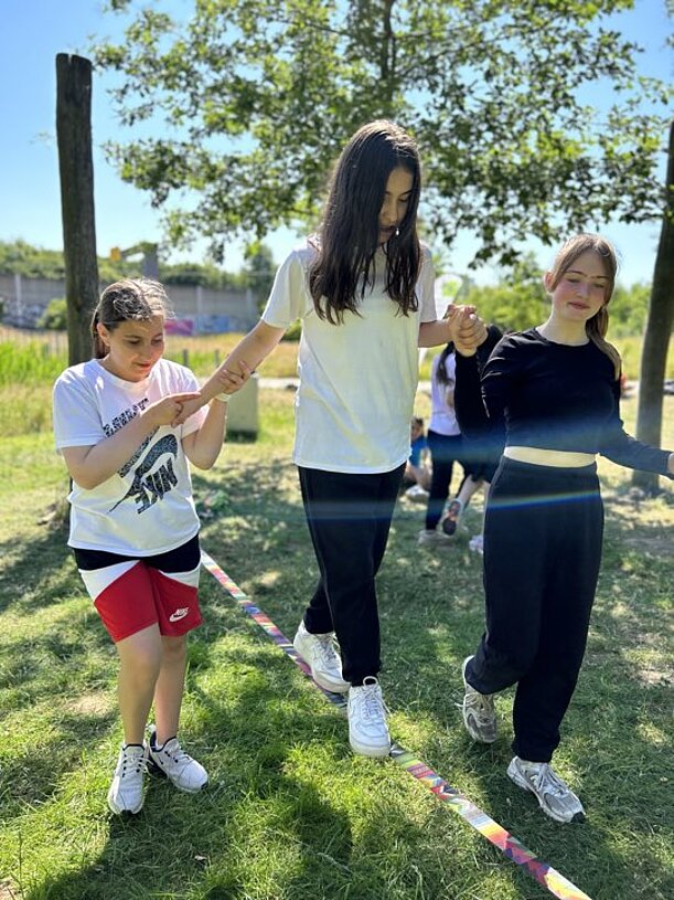 Schülerinnen balancieren auf einer Slackline im Park