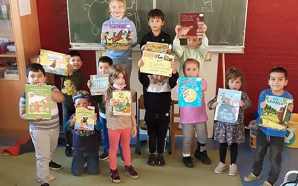 Vorschulkinder zeigen stolz ihre Bücher vor der Tafel