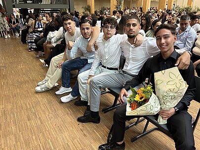 Absolventen des Jahrgangs 10 mit Blumen in Stuhlreihen bei der Entlassungsfeier