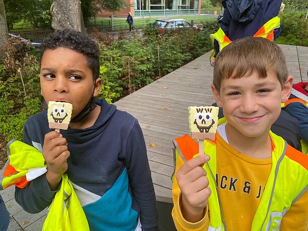 Zwei Jungen in Warnwesten mit SpongeBob-Eis nach der Müllsammelaktion