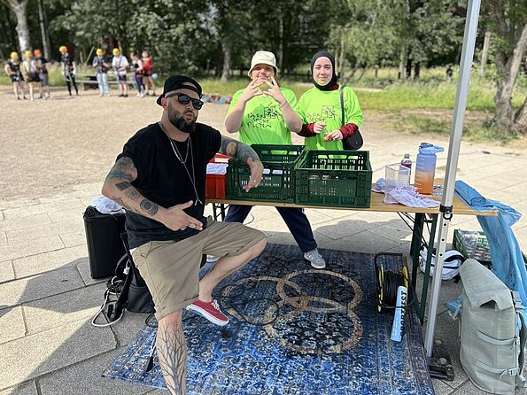 Betreuer mit Musikanlage und Helferinnen an einem Stand im Park