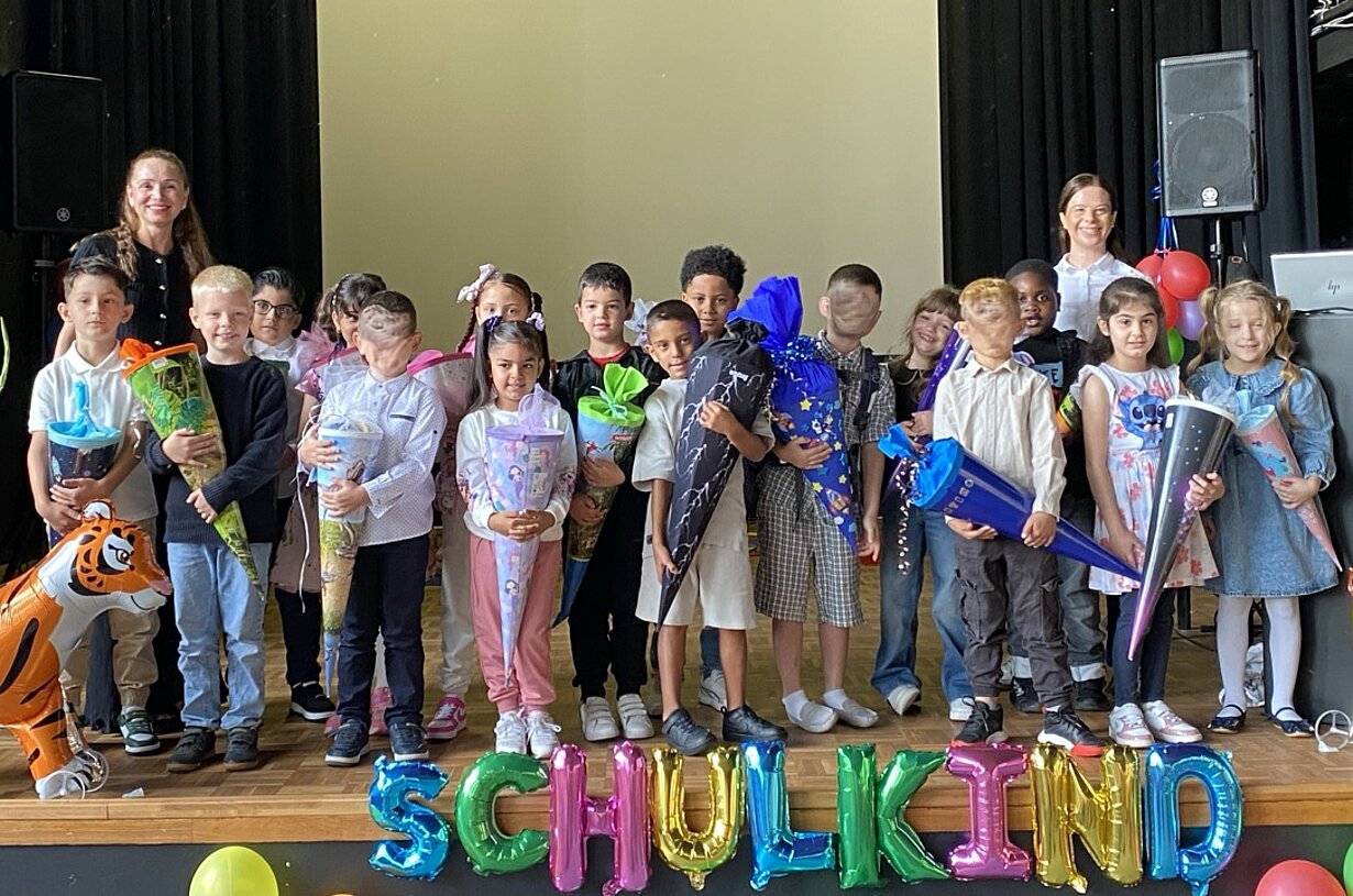 Klasse 1a mit Schultüten auf der Bühne hinter Ballonschriftzug „Schulkind“