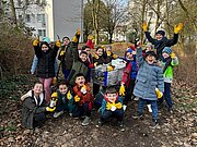 Klasse 2b mit Arbeitshandschuhen und Einkaufswagen beim Müllsammeln im Park