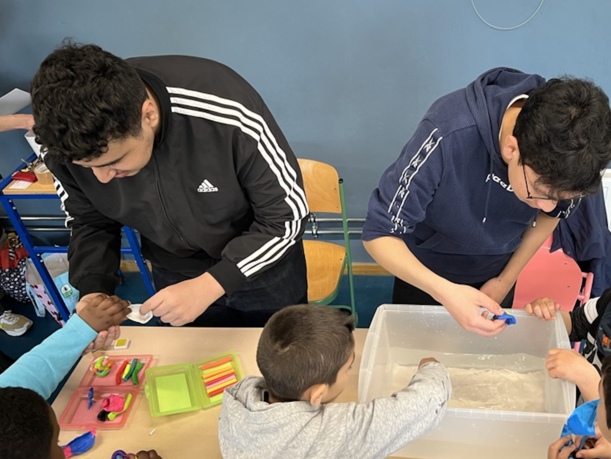 Ältere Schüler helfen Kindern bei Versuchen mit einer Wasserwanne