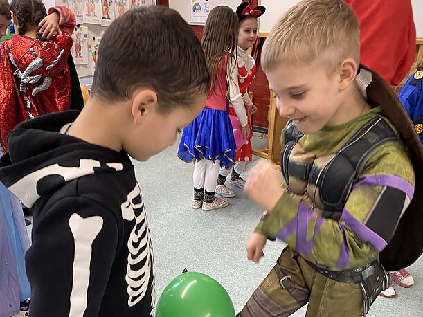Kinder als Skelett und Ninja-Turtle beim Luftballontanz im Fasching