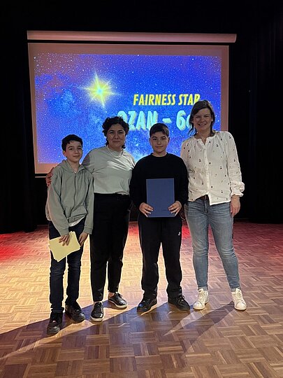 Schüler und Lehrerinnen auf der Bühne vor Leinwand „Fairness Star“