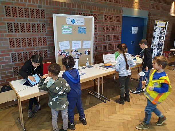 Kinder der 1c erklären Besuchern an einem Stand ihre Meeresforschung