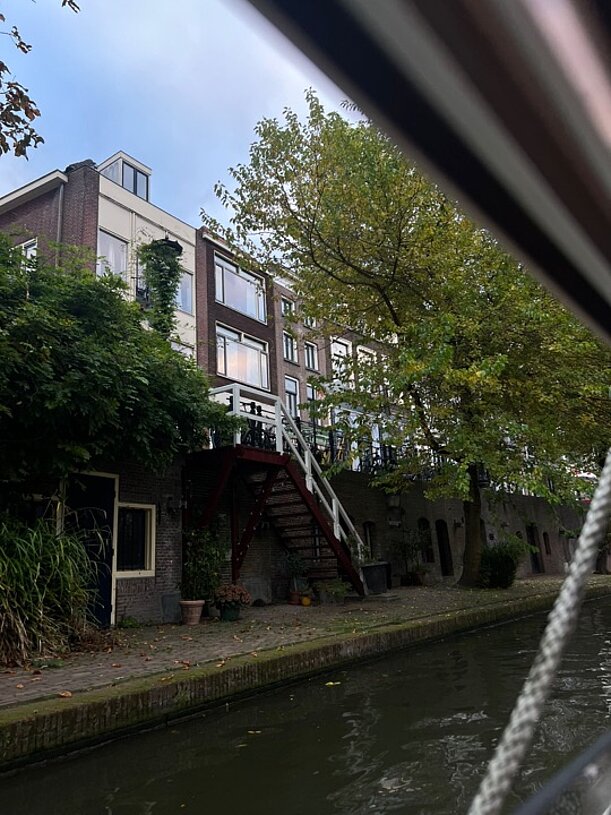 Oudegracht in Utrecht mit Backsteinhäusern und Bäumen vom Boot aus