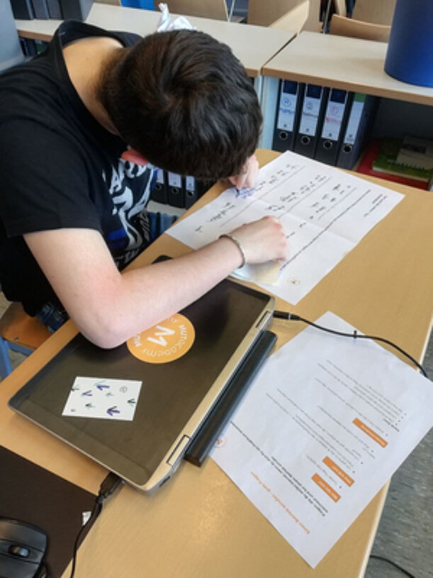 Schüler bearbeitet Arbeitsblätter am Tisch beim MUT-Workshop