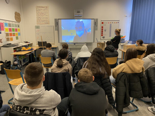 Klasse schaut im Klassenraum eine Videopräsentation auf dem Whiteboard