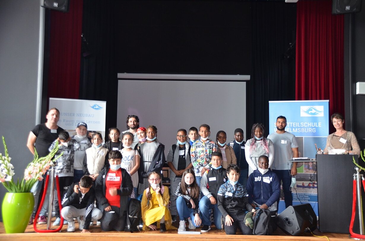 Neue Schülerinnen und Schüler als Gruppe auf der Bühne der Aula