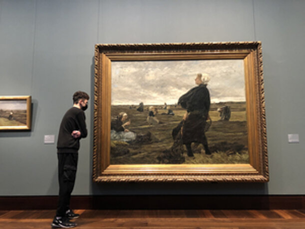 Schüler betrachtet ein großes Gemälde im Museum