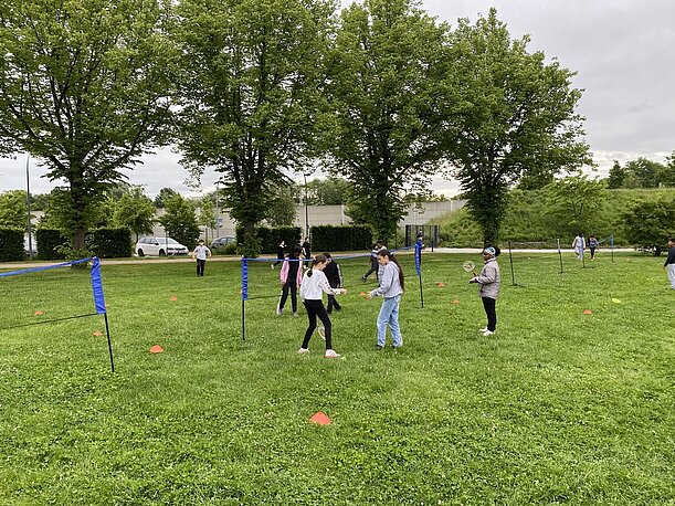 Kinder bei Laufspielen mit Fahnen auf einer großen Wiese