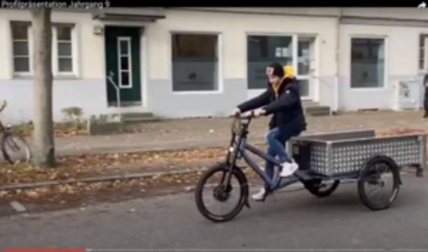 Person fährt ein Lastenrad vor einem Gebäude auf der Veddel
