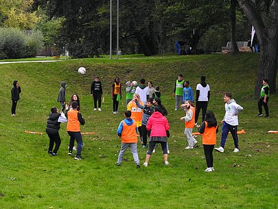 Kinder spielen Fußball auf einer Wiese im Park