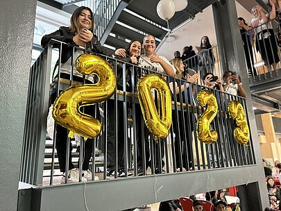 Jugendliche auf der Galerie hinter goldenen Ballonziffern 2023