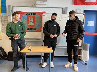 Drei Profilschüler vor Banner „Wir für Hamburg“ bei der Büchereieröffnung