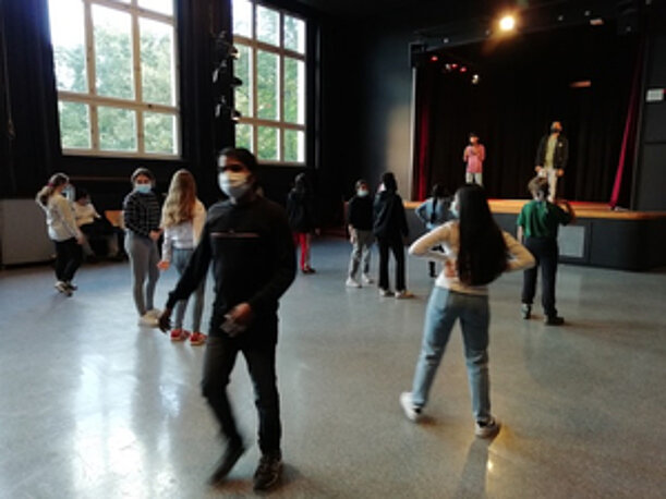 Aufwärmübungen der Schülerinnen und Schüler in der Aula