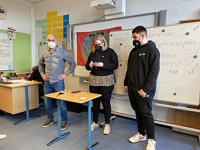 Profilschüler und Lehrkräfte an einem Tisch zur Eröffnung der Bücherei