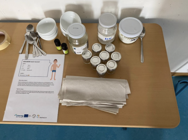Tisch mit Gläsern, Schälchen, Löffeln und Anleitung zur Deo-Herstellung