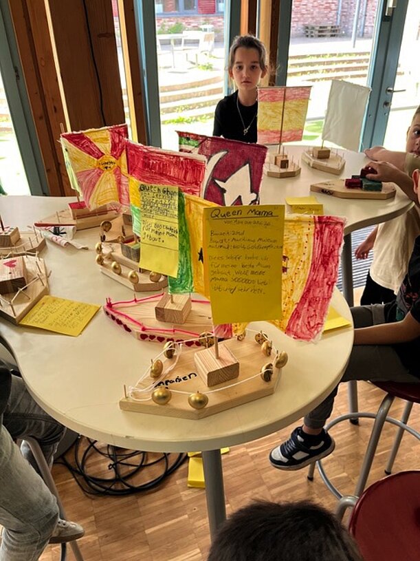 Tisch mit gebauten Holzbooten und Plakaten