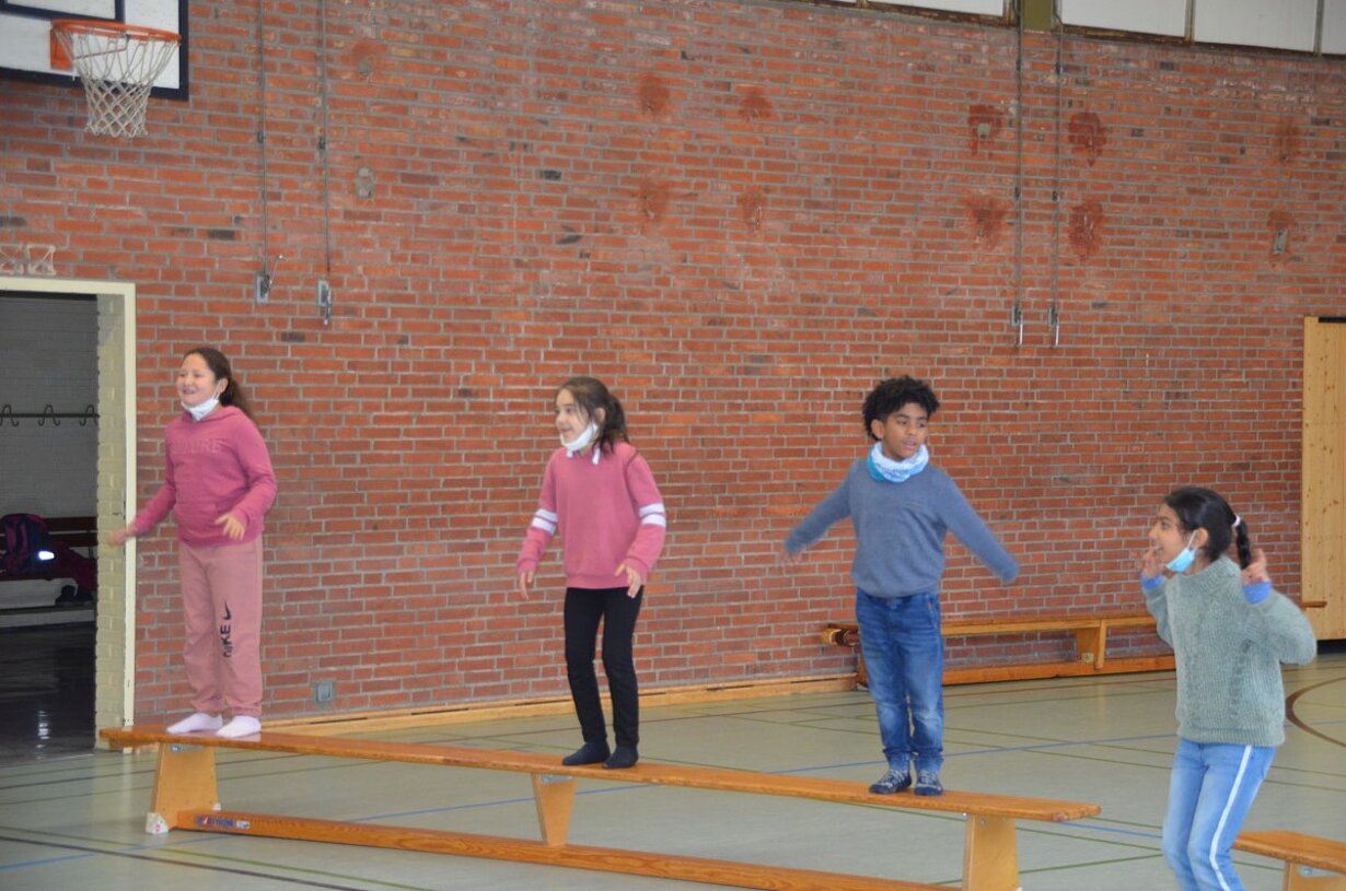 Grundschulkinder balancieren auf Turnbänken in der Singenden Turnhalle