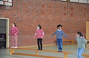 Grundschulkinder balancieren auf Turnbänken in der Singenden Turnhalle